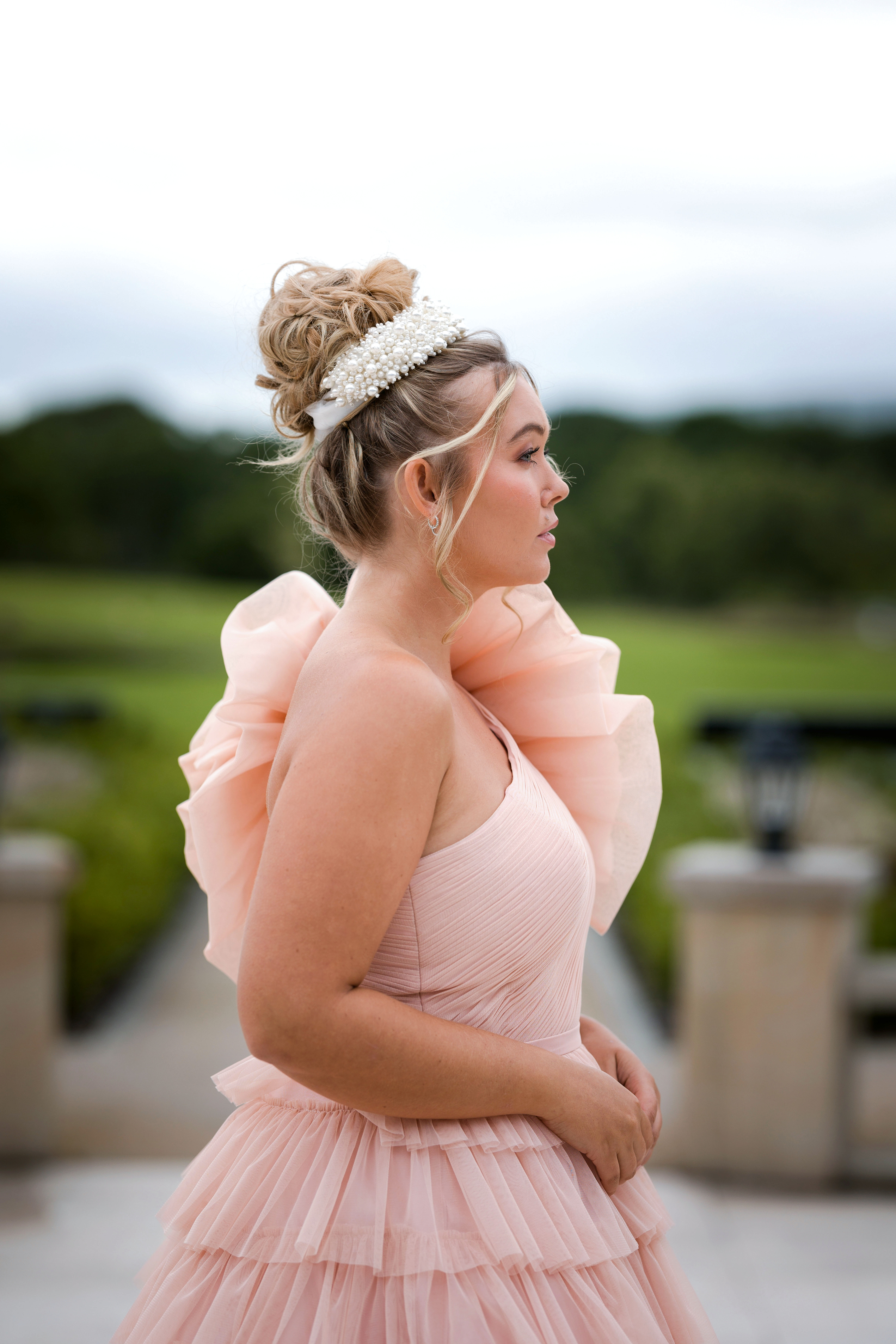 High messy bun, with statement headpiece, pink bridal Dress